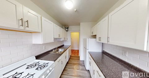 A kitchen with white cabinets and a black countertop.