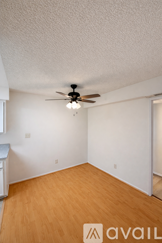 A room with a ceiling fan and wooden flooring.