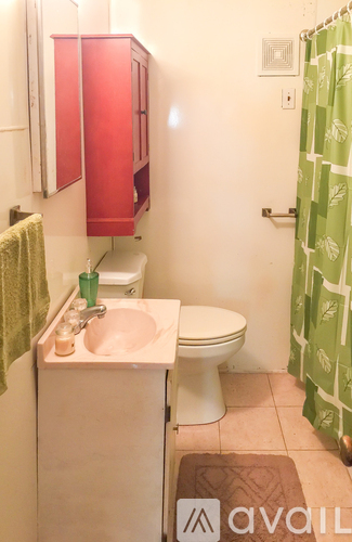 A small bathroom with a toilet, sink and red cupboards.
