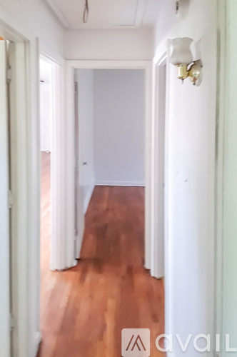 A hallway with white walls and a wooden floor.