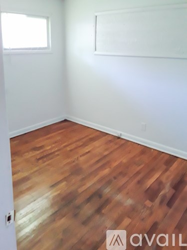 A room with wooden flooring and white walls.