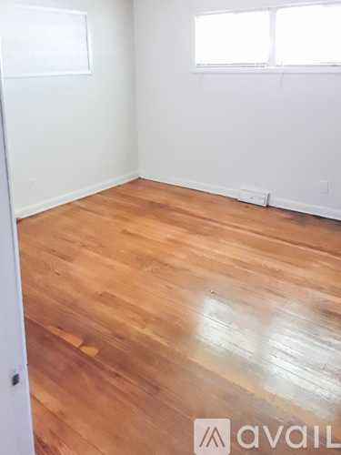 A room with wooden flooring and white walls.