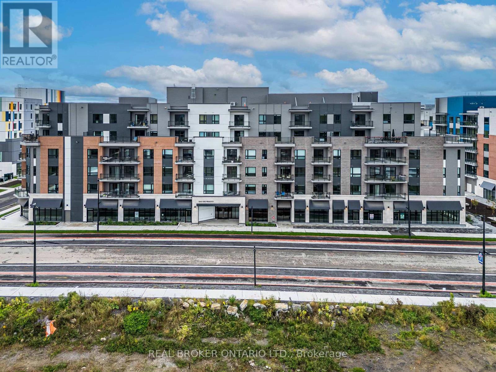 A large multi-story building with a realtor logo on the bottom left.