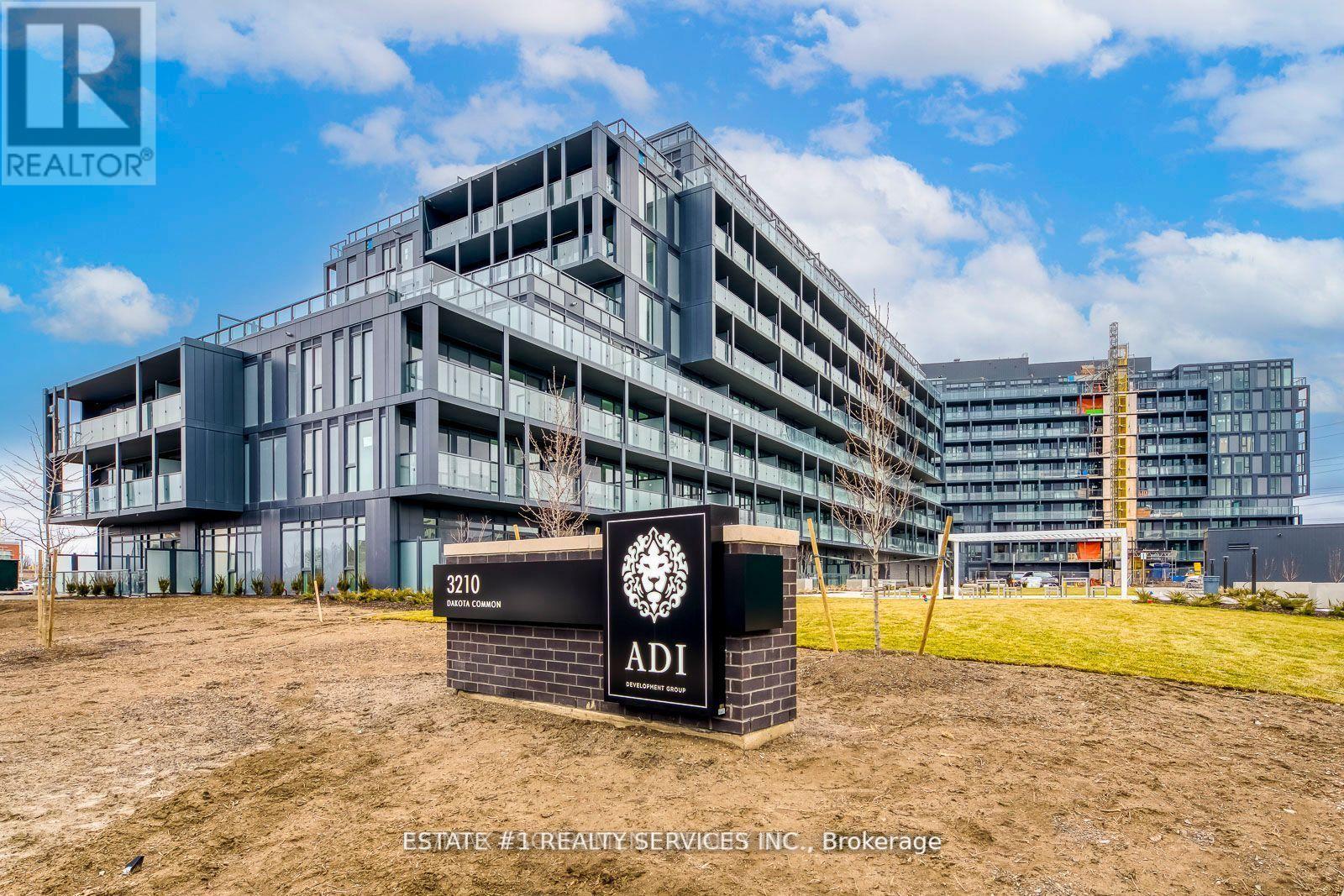 A sign for ADI Realty Services Inc. is in front of a large building under construction.