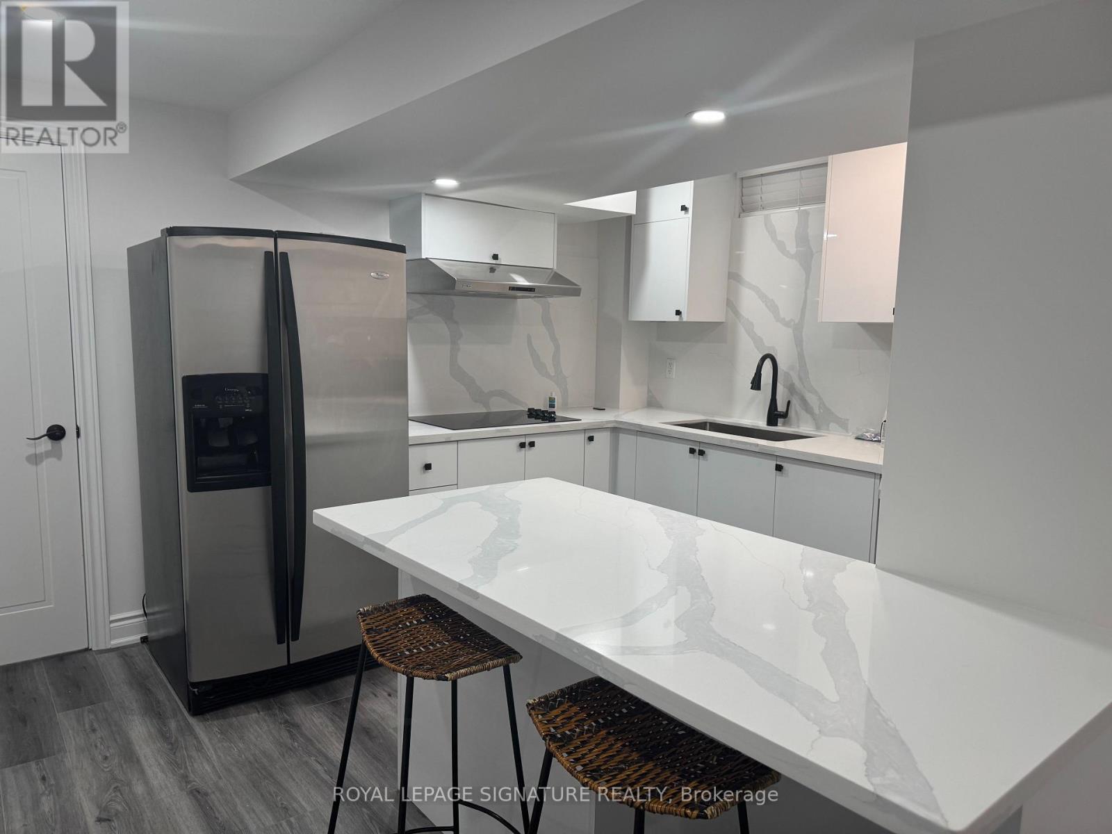 A modern kitchen with a white countertop and stainless steel appliances.