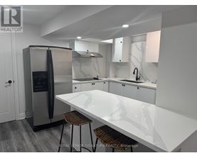 A modern kitchen with a white countertop and stainless steel appliances.