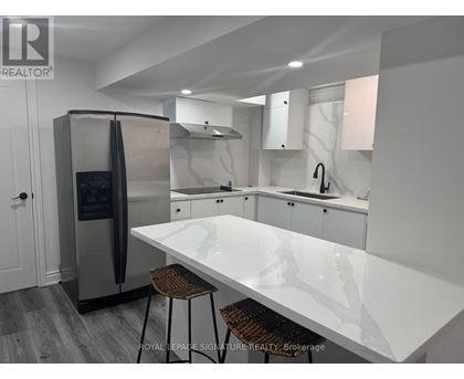 A modern kitchen with a white countertop and stainless steel appliances.