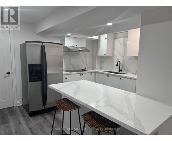 A modern kitchen with a white countertop and stainless steel appliances.