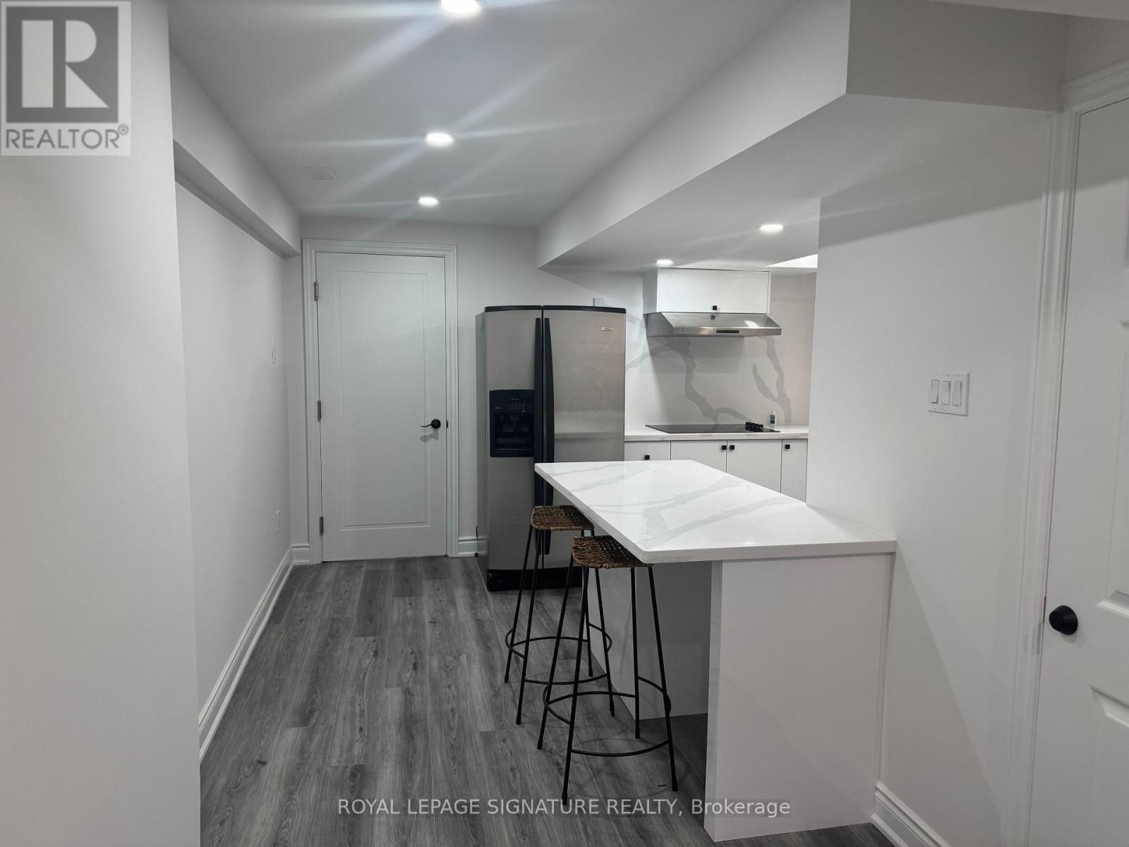 A white kitchen with a table and chairs in a room with white walls.