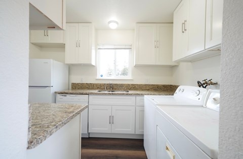 A kitchen with white cabinets and a granite countertop.