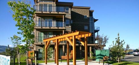 A modern multi-story building with a wooden pergola in front.