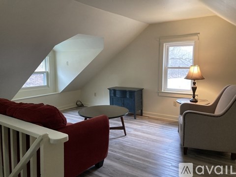 A living room with a red couch, a white armchair, and a small table with a lamp on it.