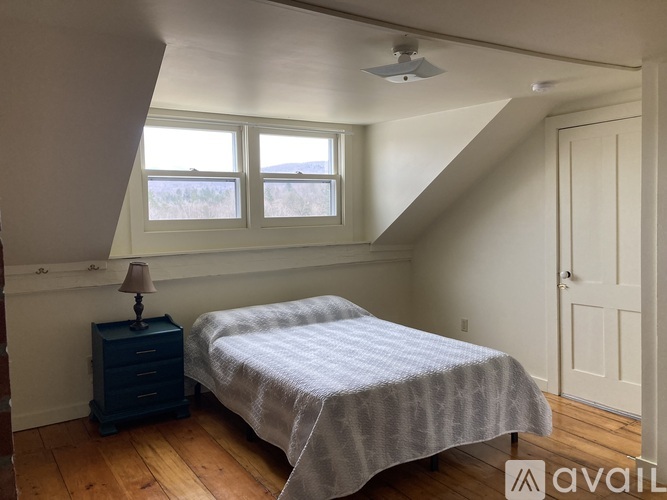 A bedroom with a bed, nightstand, and window.