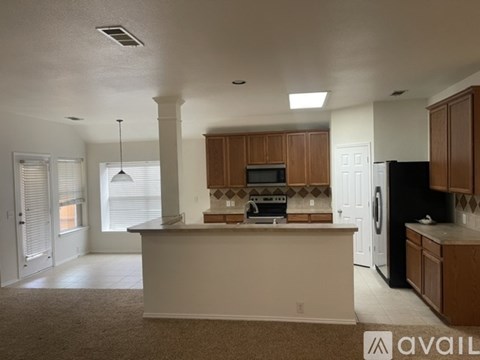 A kitchen with white walls and brown cabinets.
