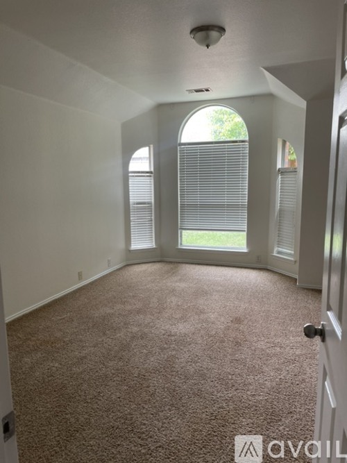 A carpeted room with a door and a window with blinds.