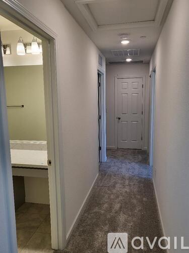 A hallway with a door and a bedroom visible through the door.