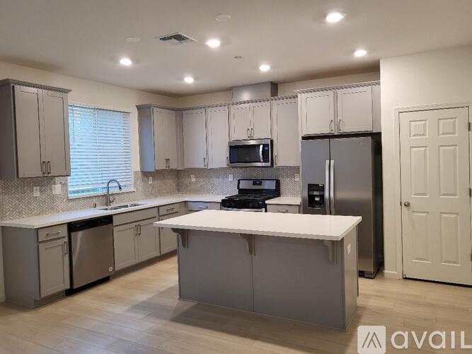 A kitchen with a white island in the middle and a refrigerator to the right.
