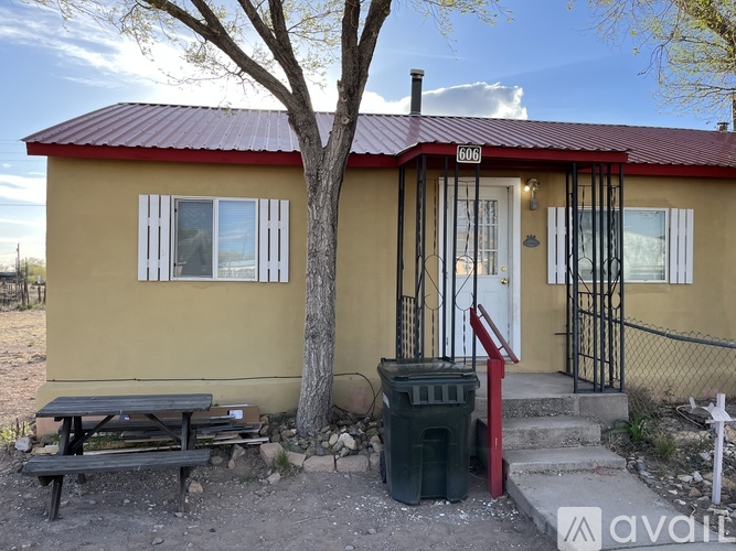 A small house with a red roof and a sign that says 606 is for sale.