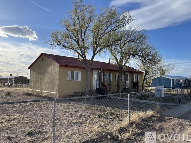 A house with a red roof and a fence in front of it.