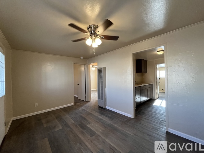 A spacious room with a ceiling fan and hardwood flooring.