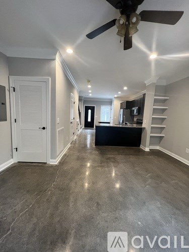 A spacious room with a ceiling fan and a staircase.