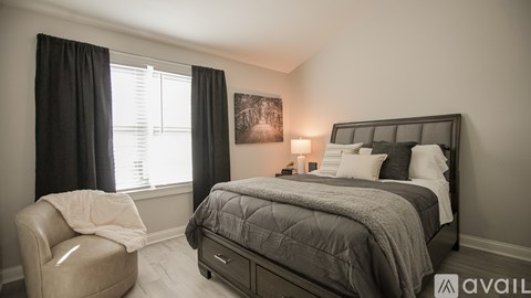 A bedroom with a large bed and a chair by the window.