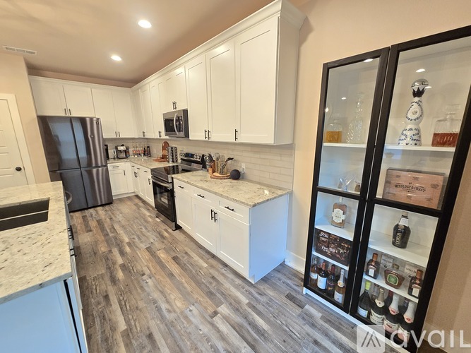 A kitchen with white cabinets and a wooden floor.