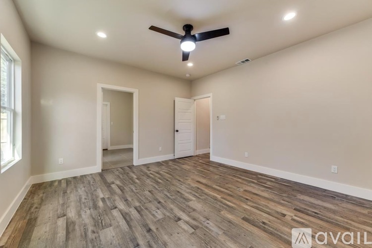 A spacious room with a ceiling fan and wooden flooring.