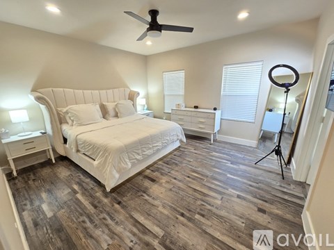 A bedroom with a large bed and wooden flooring.