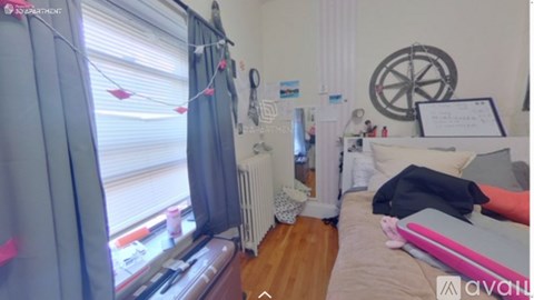 A room with a bed, a window with curtains, a radiator, and a wall clock.