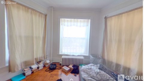 A room with a bed, a radiator, and a window with curtains.