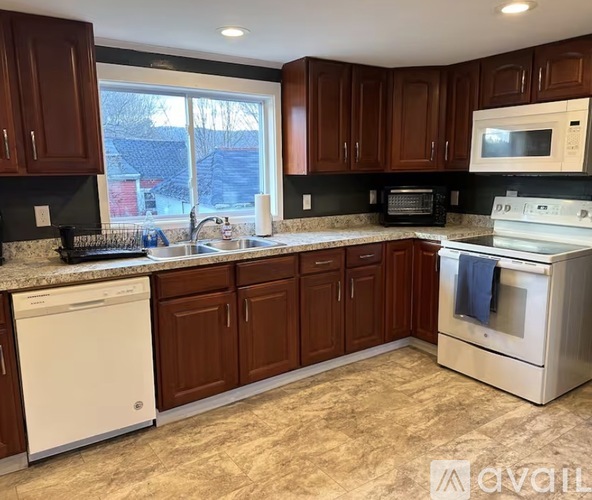 A kitchen with brown cabinets and a white dishwasher.