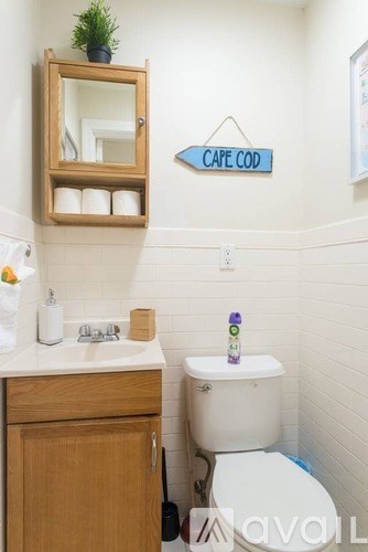 A bathroom with a toilet, sink, mirror, and a sign that says "Cape Cod".