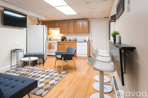 A kitchen with a white refrigerator, a black countertop, and a grey and white rug.