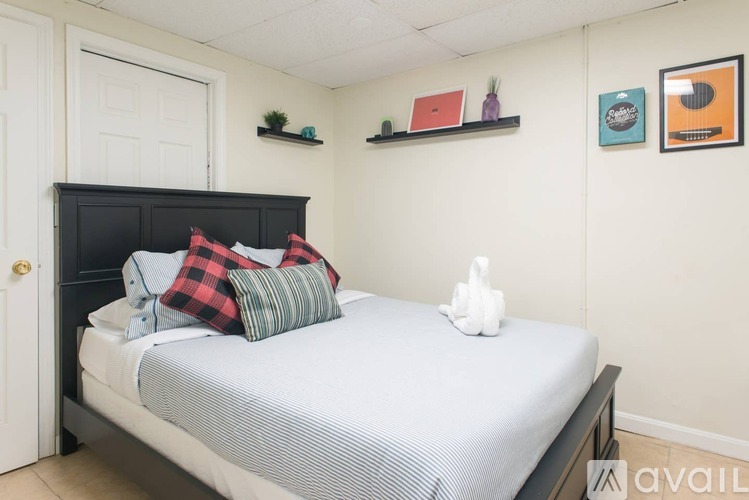 A bedroom with a bed, pillows, a nightstand, and a shelf with decorative items.