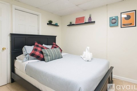 A bedroom with a bed, pillows, a nightstand, and a shelf with decorative items.