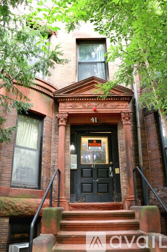 A red brick building with a black door and a sign that says "available".