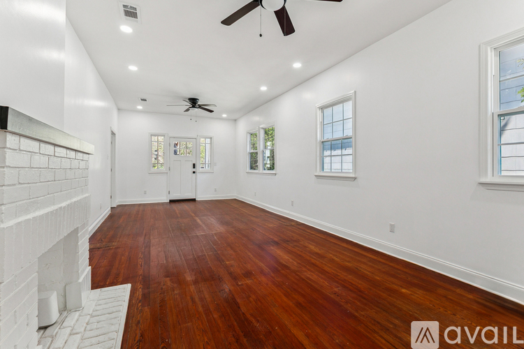 A room with wooden floors and a fireplace on the left side.