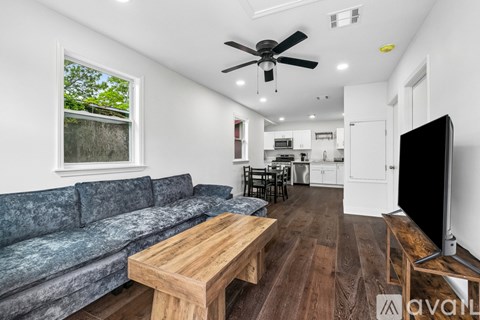 A room with wooden floors and a fireplace on the left side.