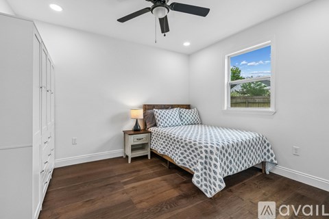A bedroom with a bed, a nightstand, and a ceiling fan.