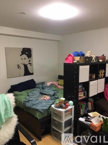 A bedroom with a bed, a shelf with various items, and a poster on the wall.