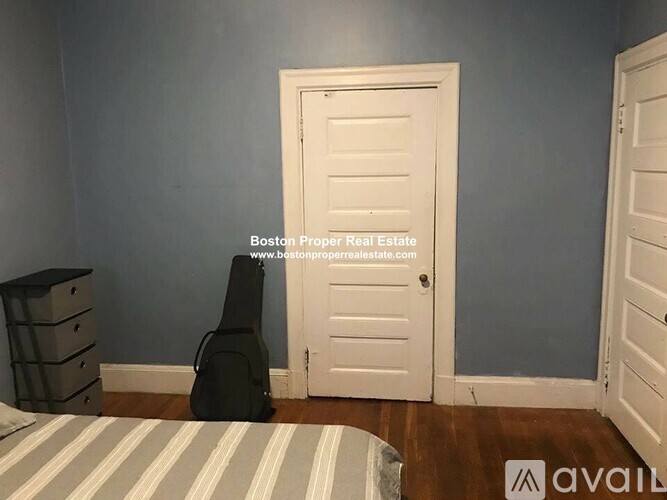 A room with a bed, a dresser, and a door.