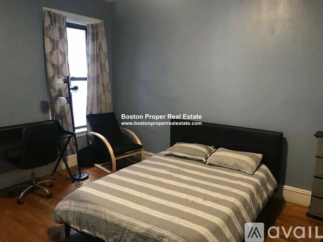 A bedroom with a bed, chair, and window.