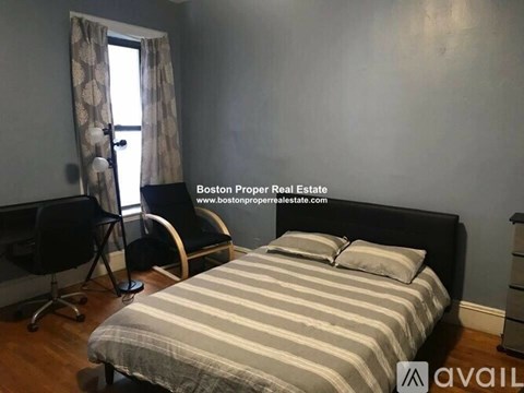A bedroom with a bed, chair, and window.
