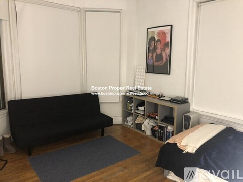 A living room with a black couch and a blue rug.