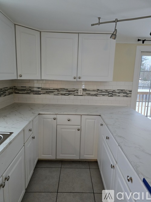 A kitchen with white cabinets and a marble countertop.