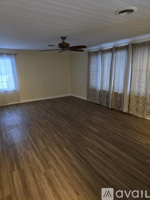 A room with wooden flooring and a ceiling fan.