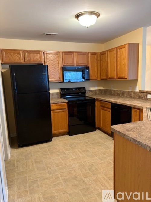 A kitchen with black appliances and wooden cabinets.