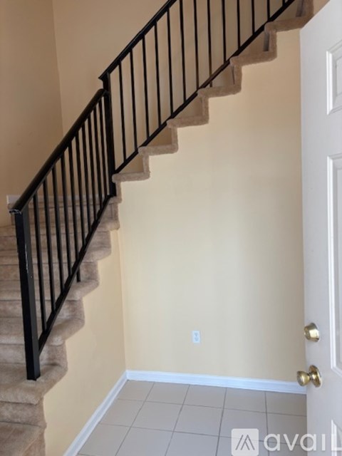 A staircase with a black railing and beige carpeted steps.