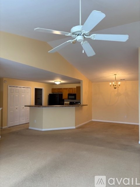 A spacious living room with a fan and a television.